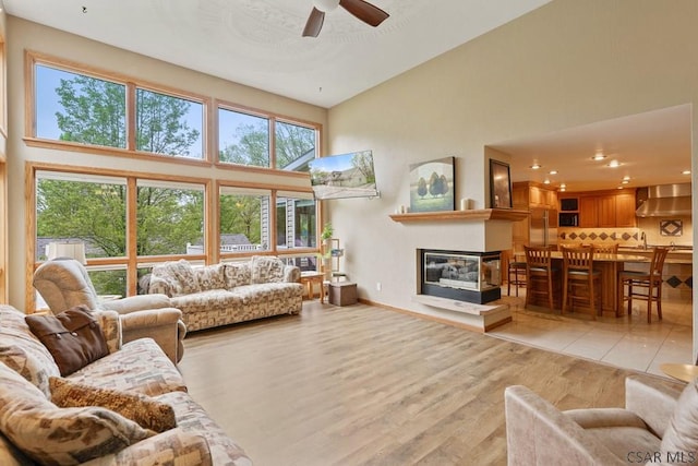 373 Hillside Ln, Somerset, PA 15501 - living room featuring a high ceiling, ceiling fan, plenty of natural light, light wood-type flooring, and a multi sided fireplace