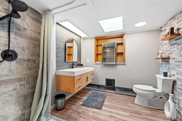 bathroom with a skylight, toilet, wood finished floors, and tiled shower