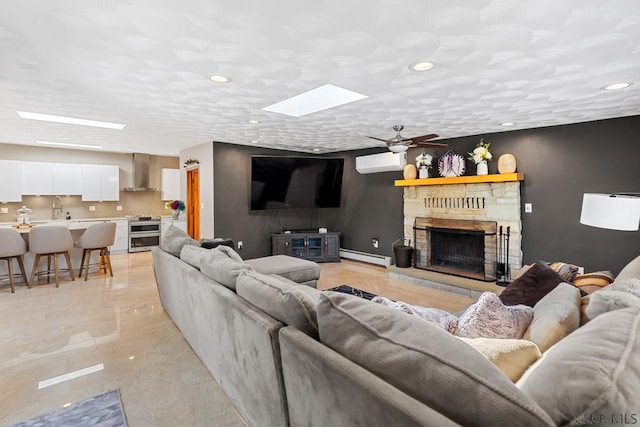 living area featuring a wall mounted AC, a skylight, a fireplace, a baseboard radiator, and ceiling fan