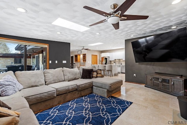 living room with recessed lighting, a textured ceiling, a skylight, and ceiling fan