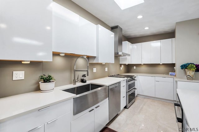 kitchen with stainless steel appliances, white cabinets, light countertops, and wall chimney range hood