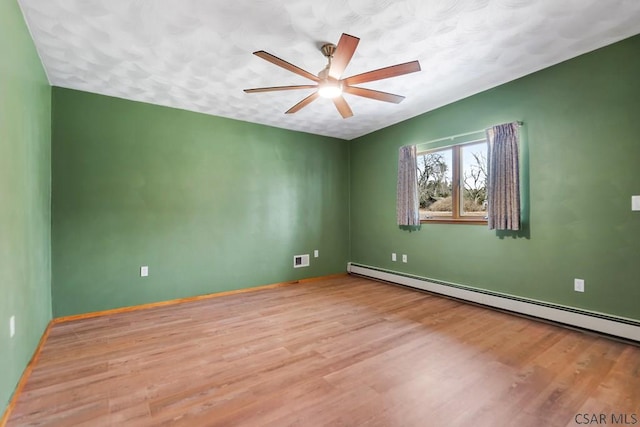 empty room with baseboards, baseboard heating, wood finished floors, and a ceiling fan