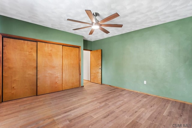 unfurnished bedroom with a closet, a ceiling fan, and light wood finished floors