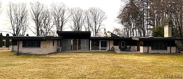 rear view of house with a yard, stone siding, and a patio area