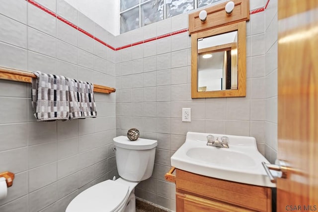 bathroom with toilet, tile walls, and vanity