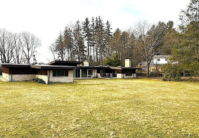 back of house with a lawn and stone siding