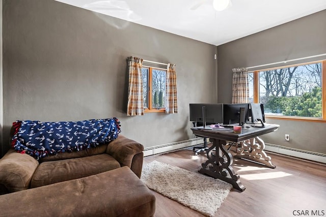 office area featuring baseboard heating, ceiling fan, and wood finished floors