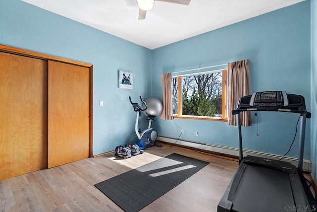 workout area with a baseboard heating unit, wood finished floors, and a ceiling fan