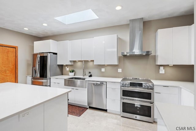 kitchen featuring modern cabinets, a sink, stainless steel appliances, wall chimney exhaust hood, and white cabinets