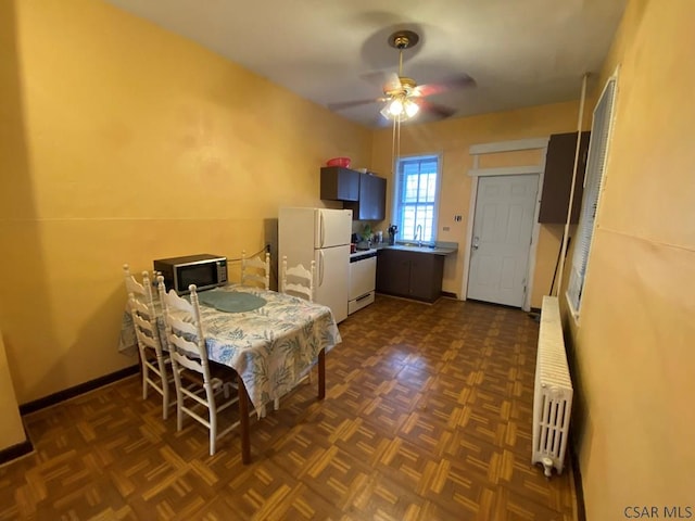 dining room featuring a ceiling fan, baseboards, and radiator heating unit