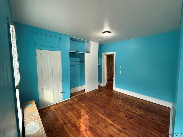 unfurnished bedroom featuring a closet, baseboards, and dark wood-type flooring