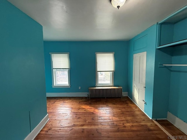 unfurnished bedroom featuring radiator heating unit, hardwood / wood-style flooring, and baseboards