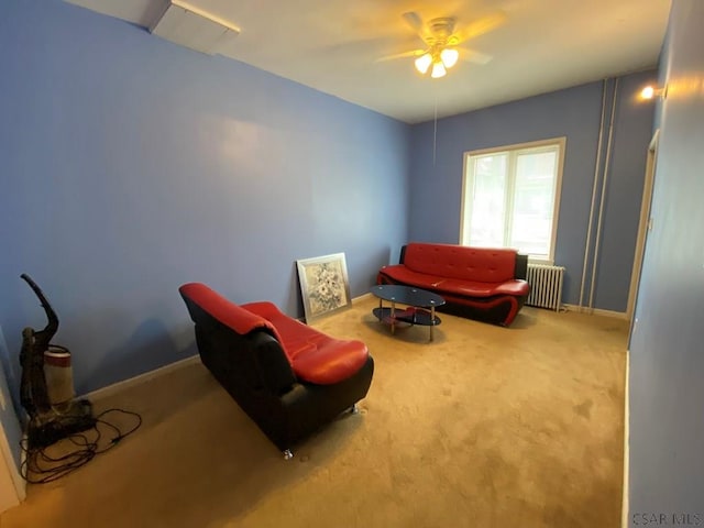 living area with radiator heating unit, carpet flooring, a ceiling fan, and baseboards