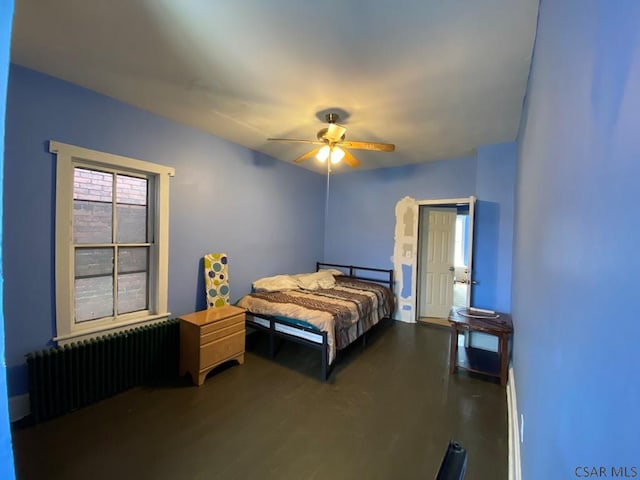 bedroom with radiator heating unit, ceiling fan, and wood finished floors