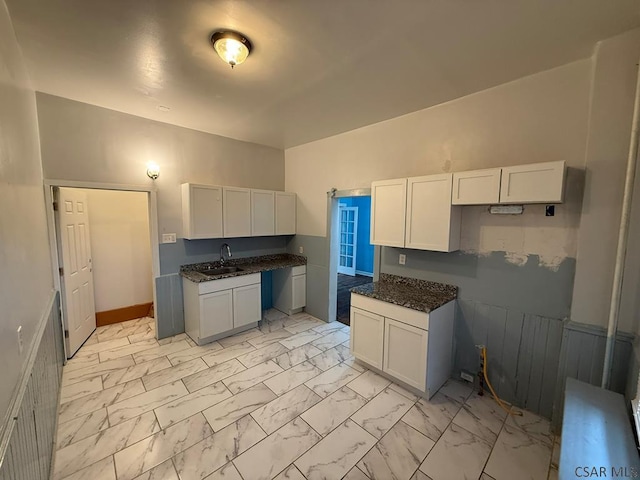 kitchen with marble finish floor, white cabinets, and a sink