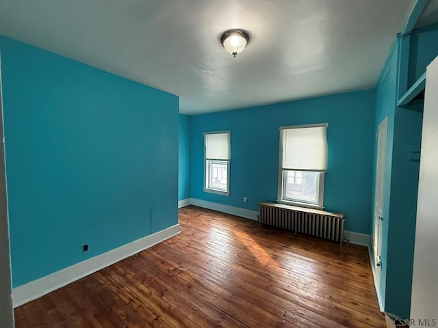 unfurnished bedroom with radiator, dark wood finished floors, and baseboards