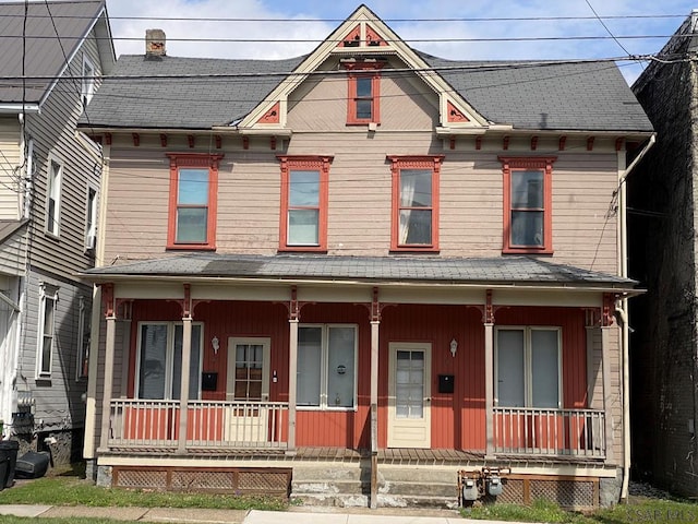 victorian-style house featuring covered porch and a chimney