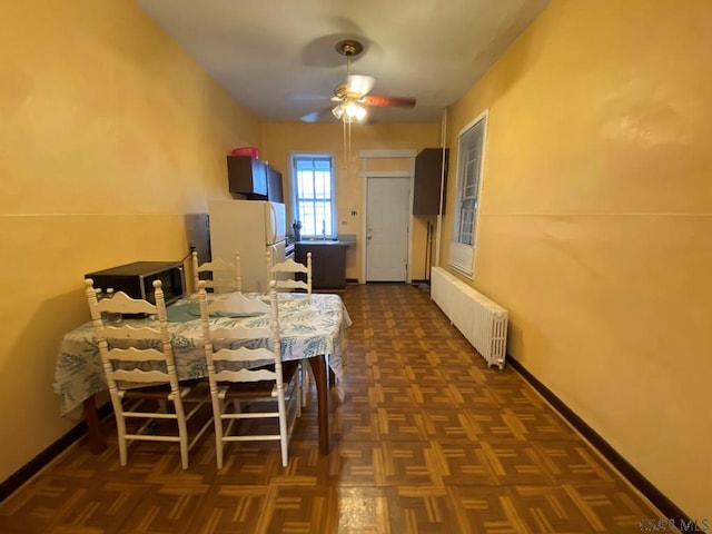 dining space featuring baseboards, ceiling fan, and radiator heating unit