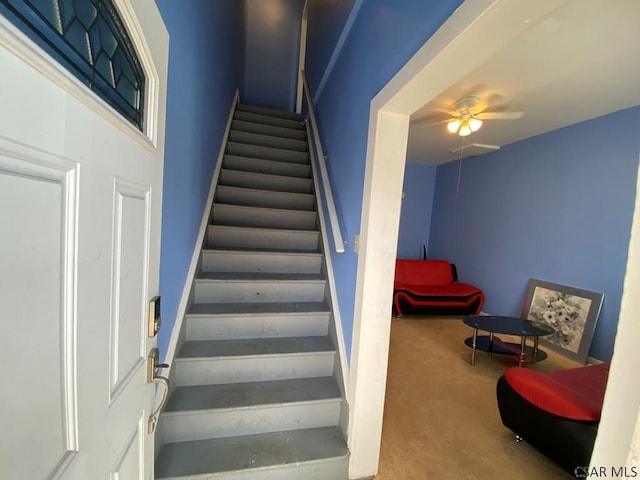 stairs featuring a ceiling fan