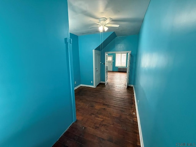 hallway featuring dark wood-style floors, lofted ceiling, radiator, and baseboards