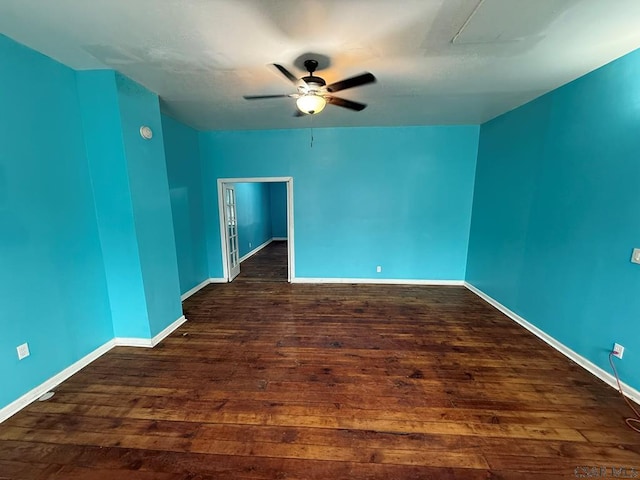 spare room featuring wood finished floors, a ceiling fan, and baseboards