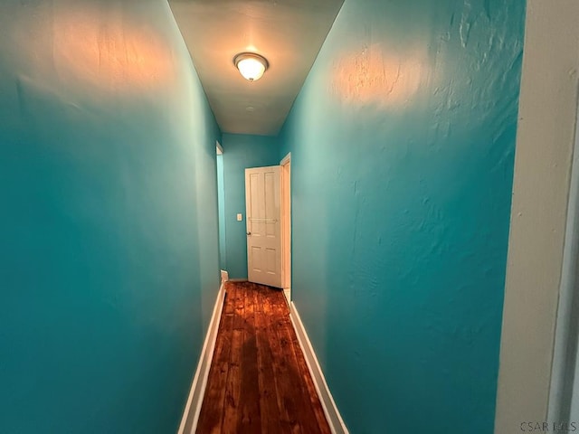 hallway with dark wood-style flooring and baseboards