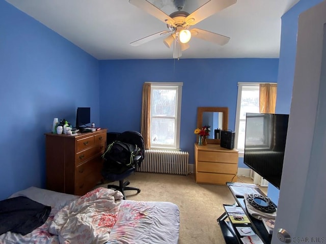 bedroom with radiator heating unit, a ceiling fan, and light colored carpet