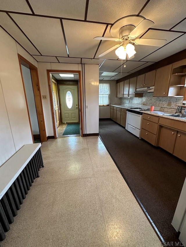 kitchen featuring sink, decorative backsplash, gas range gas stove, and ceiling fan