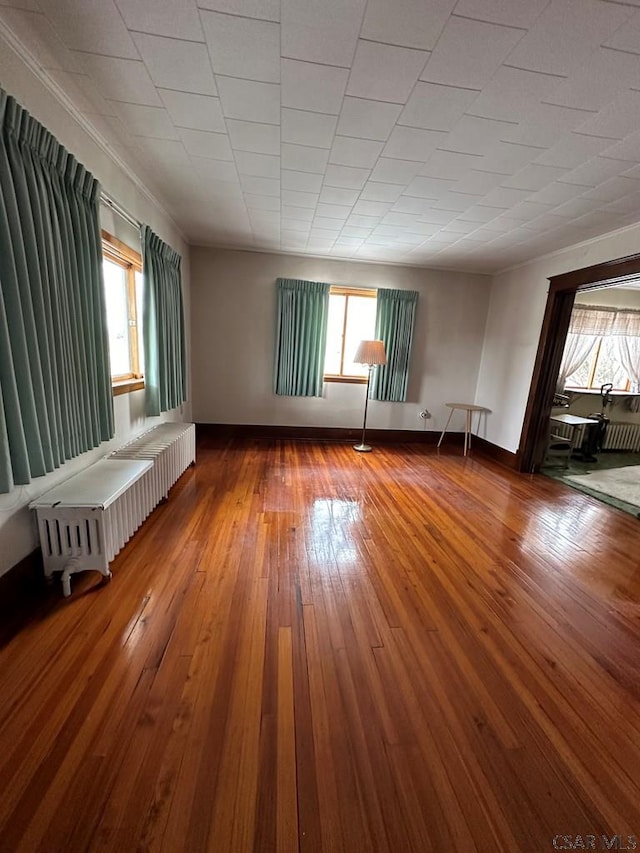 empty room featuring hardwood / wood-style flooring and radiator heating unit