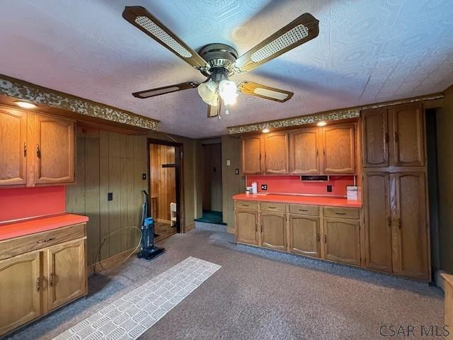 201 7th St, Windber, PA 15963 - kitchen with a ceiling fan, light colored carpet, brown cabinetry, light countertops, and wood walls