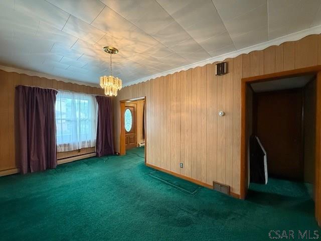 201 7th St, Windber, PA 15963 - empty room featuring a baseboard radiator, a chandelier, carpet, wood walls, and a baseboard heating unit