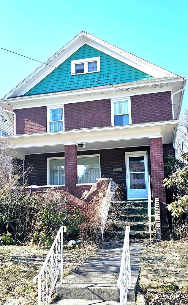 view of front of house featuring covered porch and brick siding