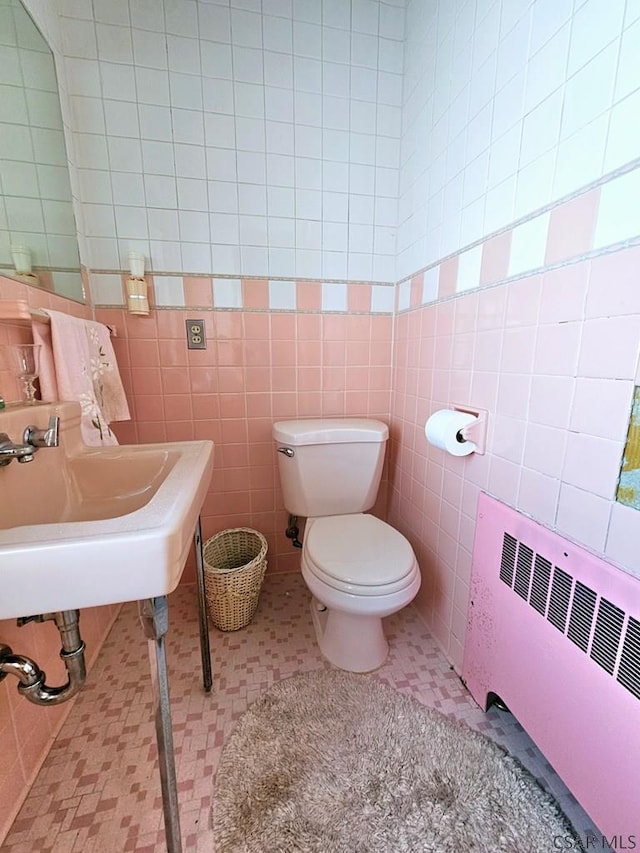 bathroom with radiator, tile patterned flooring, toilet, and tile walls