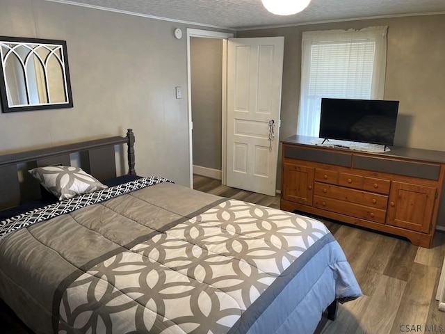 bedroom featuring crown molding, wood-type flooring, and a textured ceiling