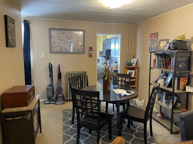 dining room with radiator heating unit, ornamental molding, and light colored carpet