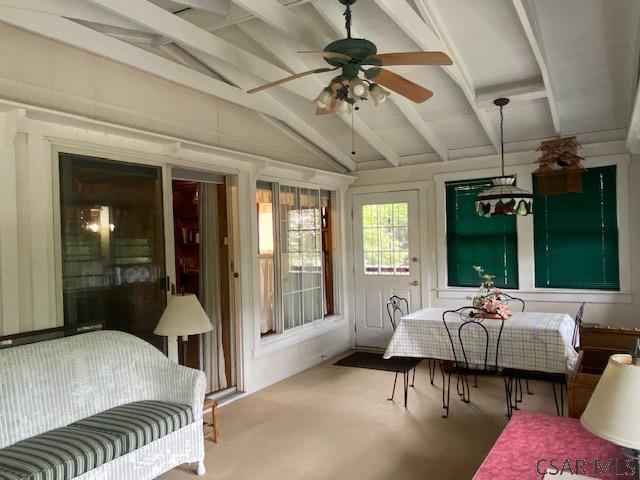 sunroom / solarium featuring vaulted ceiling with beams