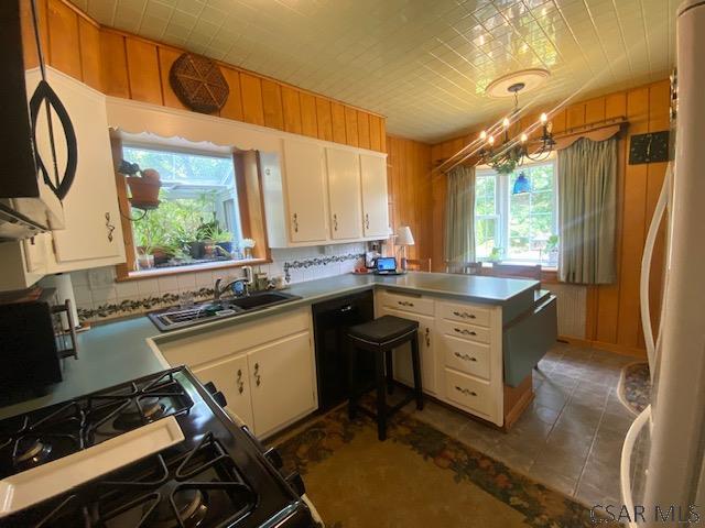 kitchen featuring pendant lighting, sink, dark tile patterned floors, white cabinetry, and black appliances