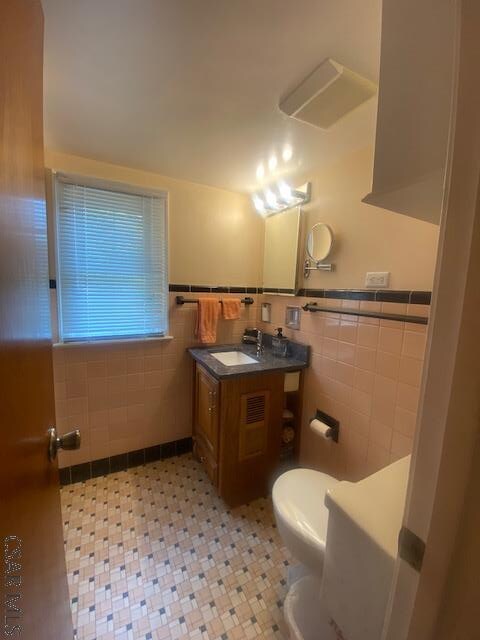 bathroom with tile walls, vanity, and toilet