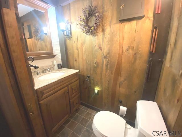 bathroom with vanity, toilet, and wood walls