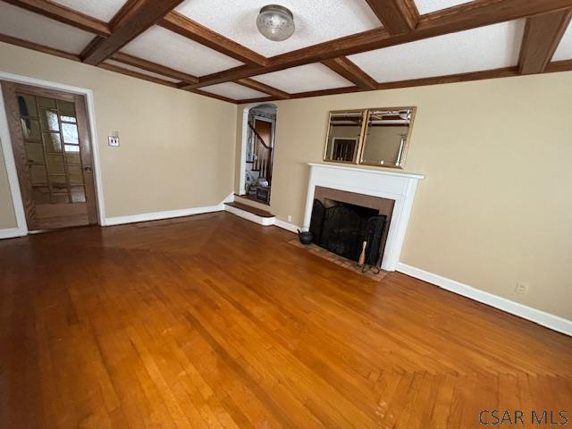 unfurnished living room featuring wood-type flooring, coffered ceiling, and beam ceiling