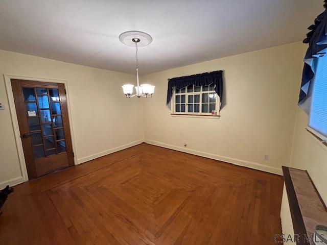 unfurnished dining area with a chandelier and dark parquet floors