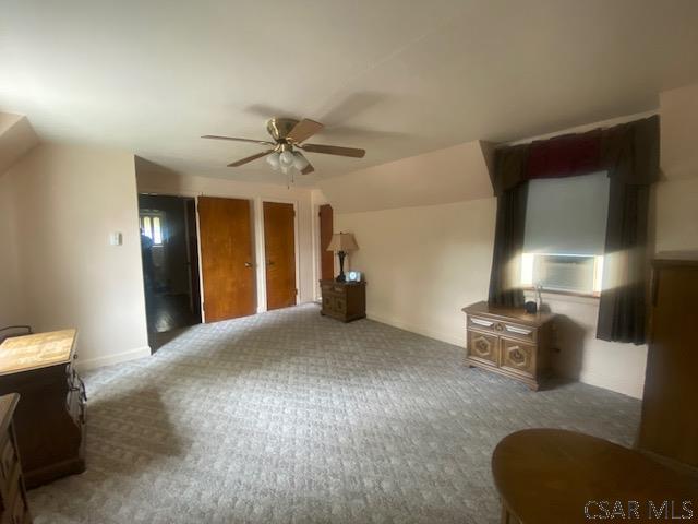 unfurnished living room featuring ceiling fan, lofted ceiling, and dark carpet