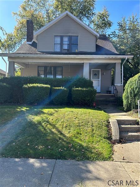 bungalow-style home with covered porch and a front lawn