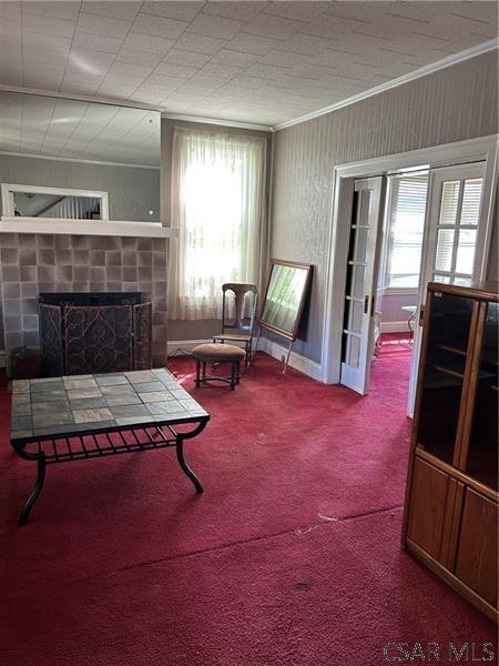 carpeted living room featuring ornamental molding, plenty of natural light, and a tile fireplace