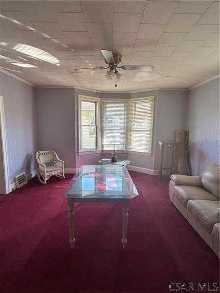 living room with ornamental molding, plenty of natural light, carpet flooring, and ceiling fan