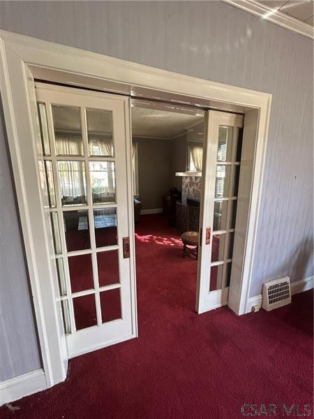 doorway featuring french doors, a fireplace, and carpet flooring