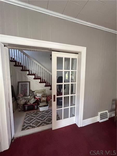 doorway featuring crown molding and carpet