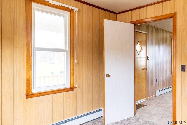 interior space with baseboard heating, ornamental molding, and wood walls