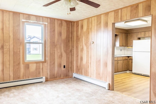 carpeted empty room with wooden walls, ceiling fan, and baseboard heating