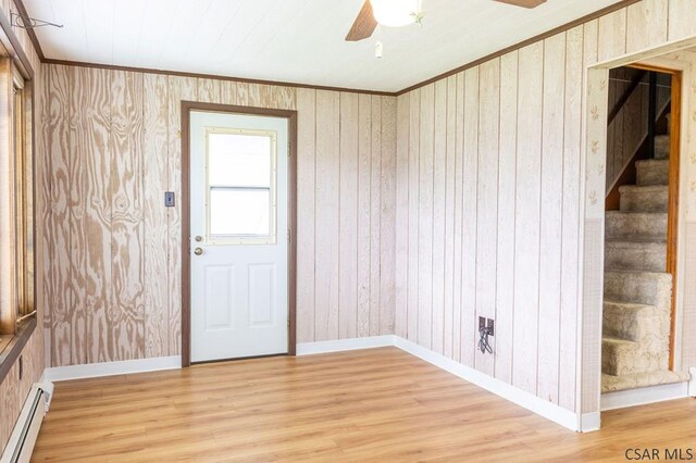 entrance foyer with a baseboard heating unit, hardwood / wood-style flooring, wooden walls, and ceiling fan